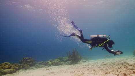 scuba diver jugando con scooter submarino sobre suelo arenoso