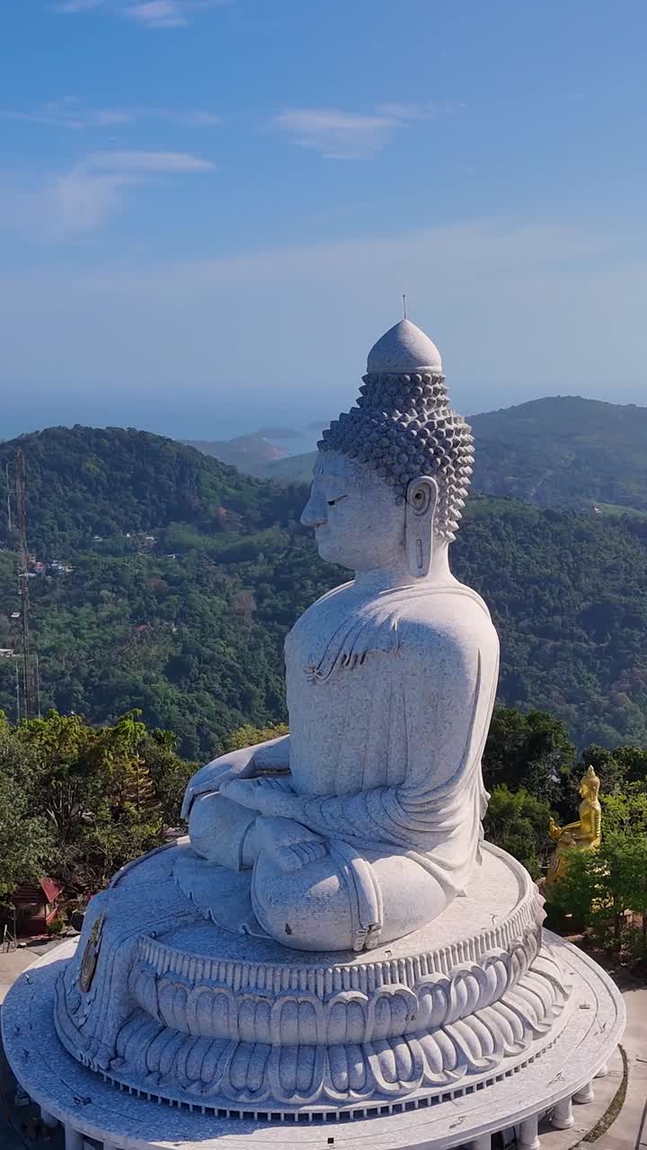 las imágenes del dron capturan la serena estatua del gran buda con vistas a las exuberantes colinas y el mar de andamán en phuket, tailandia.