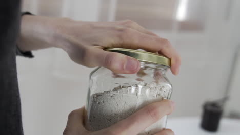 slow motion shot as opening a jar full with white powder, flour, gluten free baking