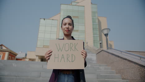 Woman Holding a Sign Reading "Work Hard"