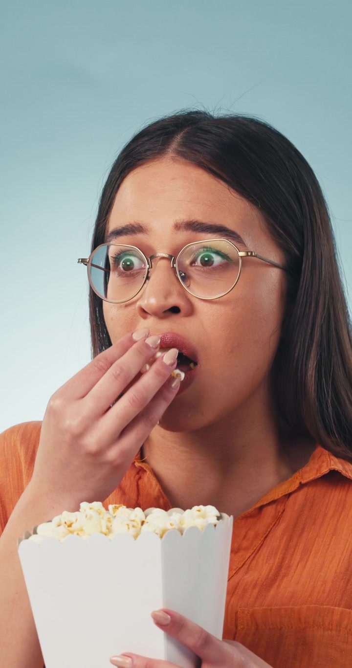 Giovane donna che mangia popcorn guardando un film