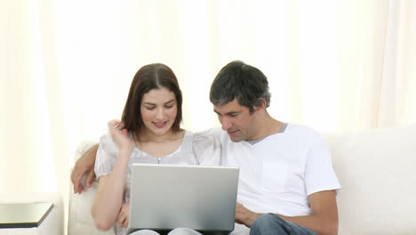 pareja usando una computadora portátil en el sofá