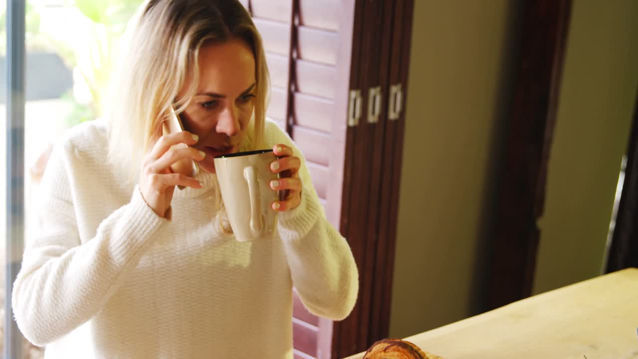 mujer hablando por teléfono móvil mientras toma café 4k