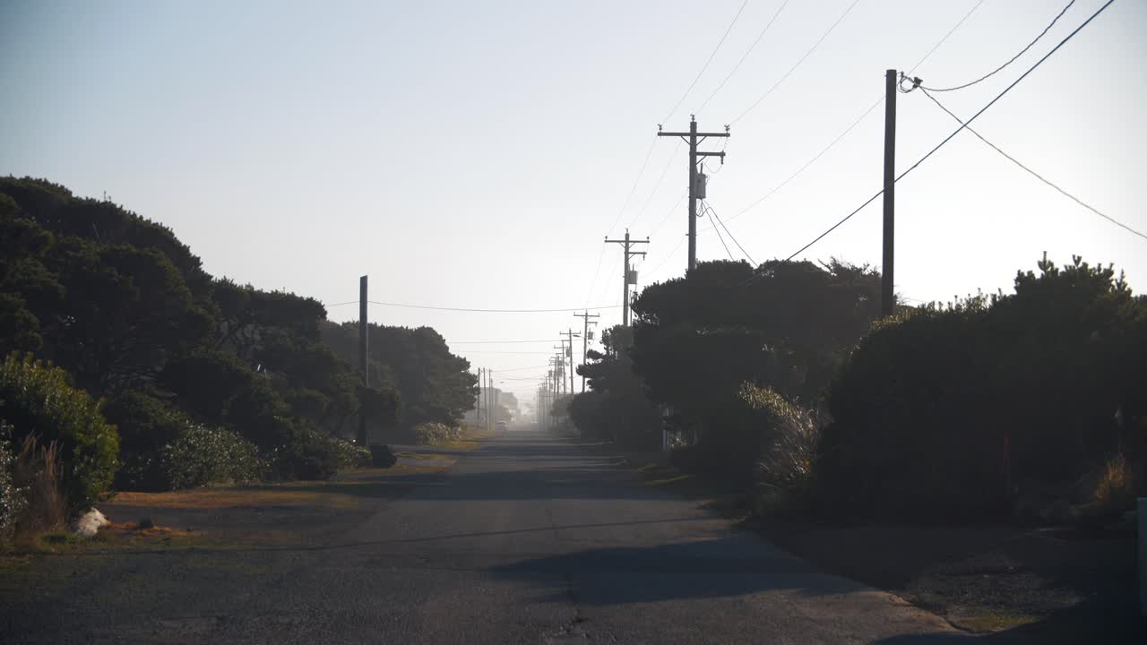 4k footage of a long empty street next to the beach with some dust of the ocean in the sky - slow motion - Rockaway Beach Oregon, USA