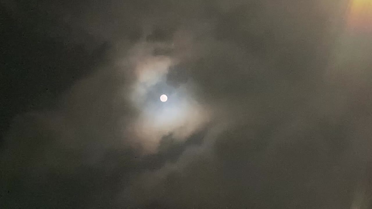 primer plano de la luna llena en la oscuridad cubierta por la nube no completamente cubierta