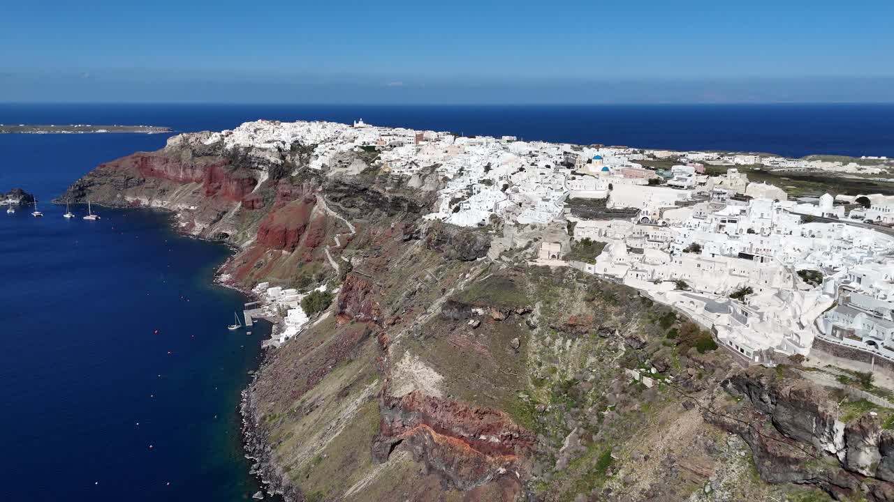 Vista aérea dramática mostrando as íngremes falésias vulcânicas de Santorini, Grécia. Uma ampla imagem de drone destacando as formações geológicas escuras encontrando o vasto oceano Egeu.