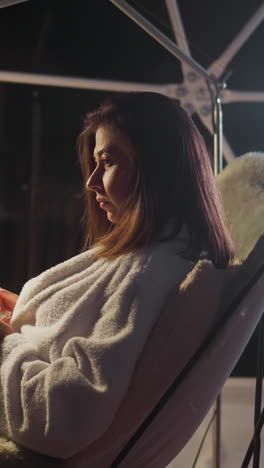 mujer sombría disfruta de café en una habitación débilmente iluminada relajándose en un programa de glamping. actitud depresiva hacia la vida y la soledad. relajación sola entre la naturaleza virgen