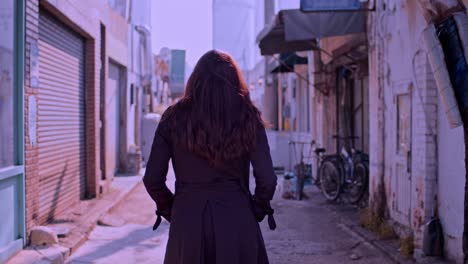 female caucasian white woman model is walking on the narrow urban town city street and walls