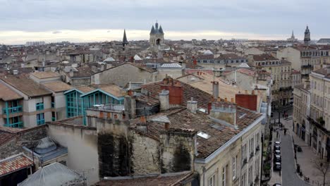 city of bordeaux france rooftops showing cailhau city gate and pigeon flocks flying, aerial pedestal rise reveal shot