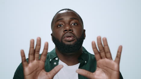 Portrait-upset-african-man-showing-please-gesture-on-light-background.