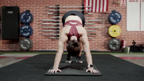 woman practicing downward-facing dog yoga pose in gym