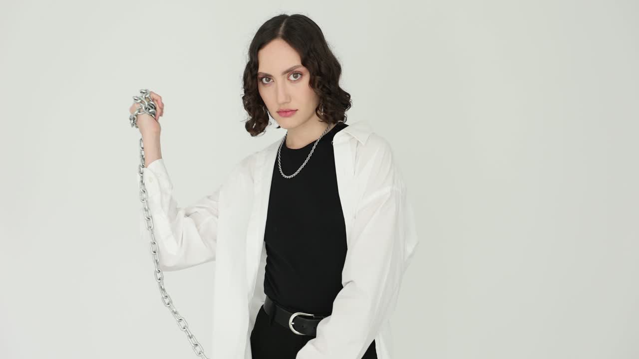 Confident Woman Posing with a Metal Chain Against a White Background