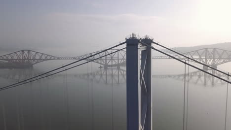 aerial footage of the old forth road bridge with the forth railway bridge in the background on a sunny day at south queensferry in west lothian, scotland