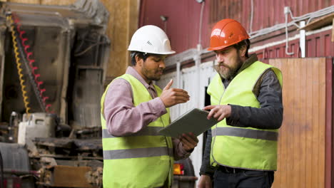 boss and worker wearing vests and safety helmets organizing a truck fleet in a logistics park while they consulting a document 7