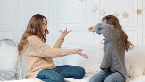 Smiling-ladies-making-dancing-gestures-on-double-bed-in-living-room.