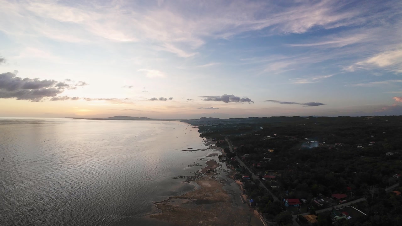 Coastal Sunset Scene. Tranquil Coastal Settlement Featuring Reflective Sea And Cluster Of Houses. Picturesque Seaside Community With Treelined Coast And Pastel Sky During Sunset