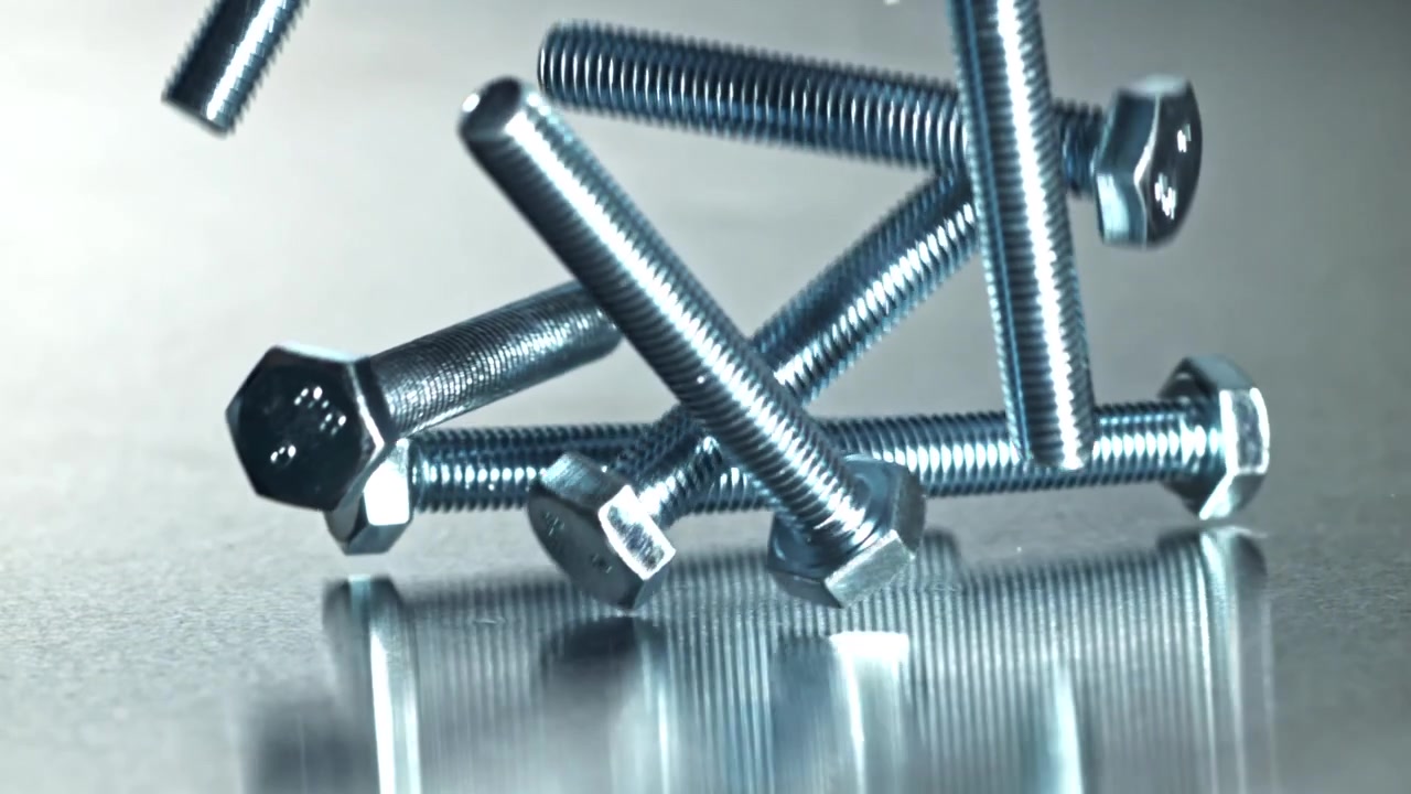 Bulloni metallici che cadono al rallentatore su una superficie riflettente