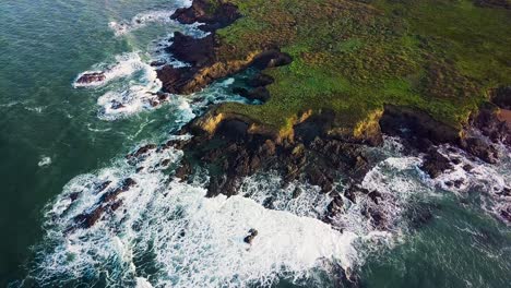 waves crash against rocky cliffs on the california coast at sunrise