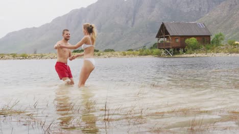 caucasian couple having a good time on a trip to the mountains, wearing bathing suits and dancing in