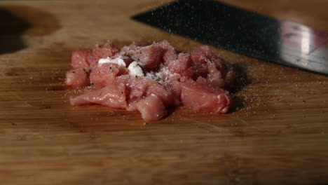 pieces of pork being seasoned with salt