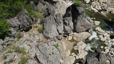 a high shot moves forward and rises, starting on river and rocks, flowing with the current, ending with full river view and scenic landscape at tinipak river, philippines