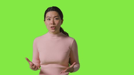좌절 된 분노 한 여자 의 스튜디오 초상화 는 녹색 스크린 에 맞서 서 있는 카메라 에 소리 지르고 있다