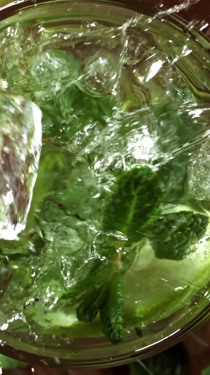 Vettä kaadetaan virkistävään Mojito-cocktailiin mintun ja limen kanssa