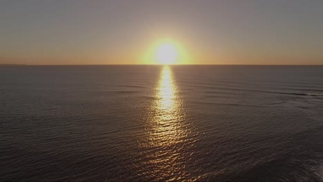 Camera-moving-from-left-to-right-with-sunrise-at-the-center-of-frame-scanning-water-and-landscape