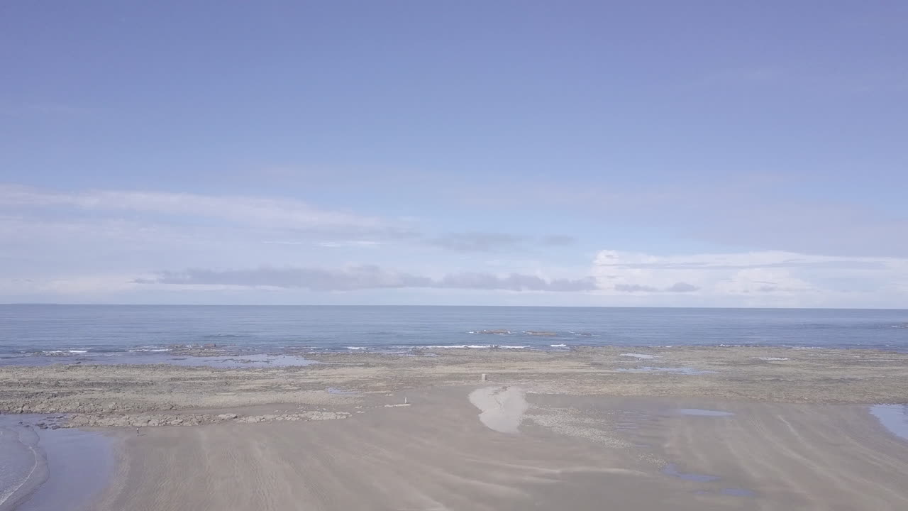 코스타리카 남쪽 푼타레나스에 있는 고래 꼬리 모양의 푼타 우비타 바위 지점으로 이어지는 모래 위를 날아가는 공중 샷