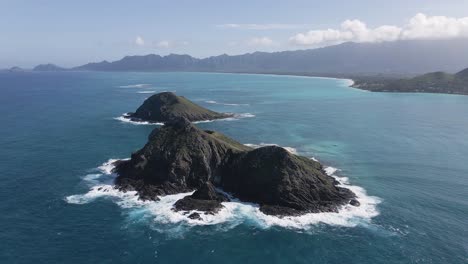 Crashing-waves-against-Mokulua-Twin-Islands-and-coastline-of-Hawaii-in-background-during-sunny-day