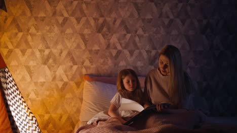 mother turns page reading fairy tale to get child to bed