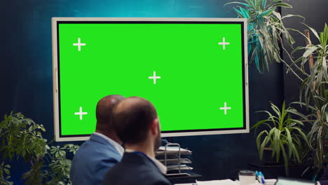 equipo de inicio viendo un video de campaña publicitaria en una pantalla verde,