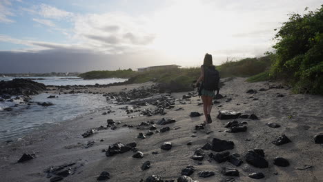 female backpacker walking along playa de la estacion in the galapagos with ocean waves gently breaking. slow motion