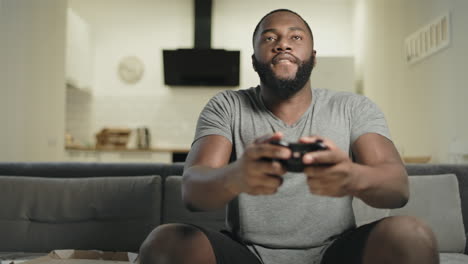 un hombre afroamericano loco jugando a videojuegos en la cocina de su casa.