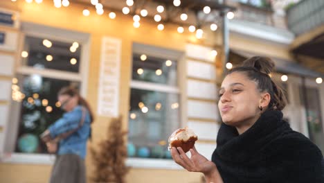 una mujer comiendo rosquillas fuera de la cafetería.