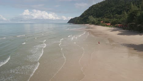 Luftdrohnenaufnahme-Aus-Dem-Niedrigen-Winkel-Eines-Tropischen-Strandes-Mit-Einem-Mann,-Der-Auf-Der-Insel-Koh-Chang-In-Thailand-Läuft