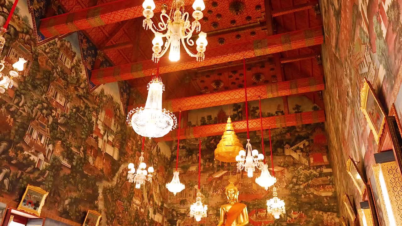 Chandeliers illuminate ornate temple interior with murals
