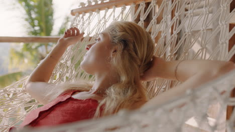 young woman in hammock enjoying comfortable lifestyle on vacation in holiday resort swaying peacefully on lazy summer day in tropical paradise cabin