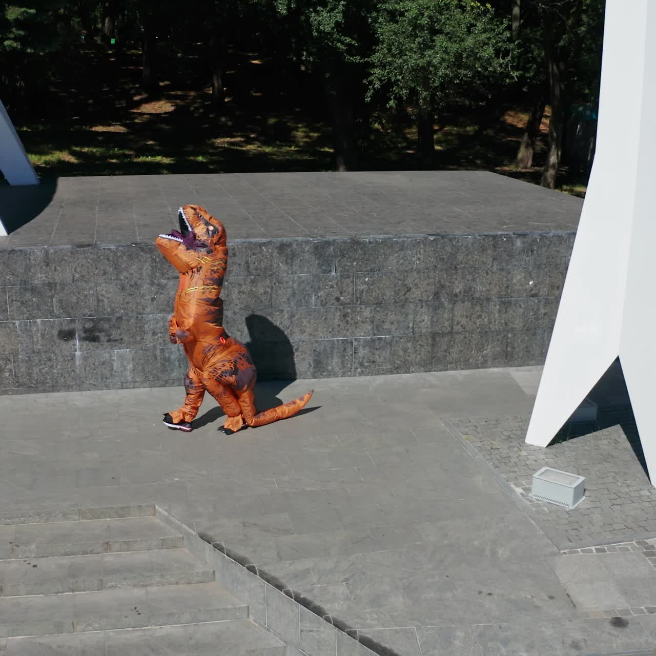 Orange funny dragon costume walking by in the city. Active person wearing blow-up dragon suit