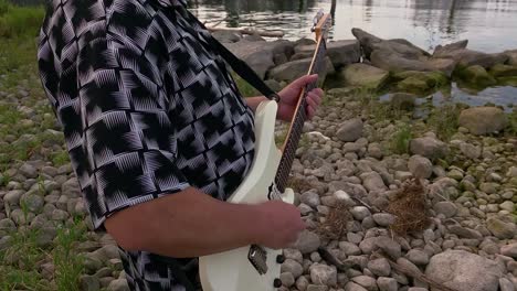 man playing guitar by the lake