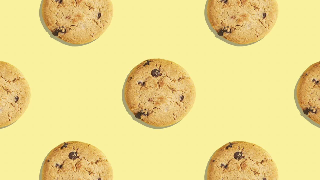 4k video pattern of american biscuits with chocolate pieces decreasing on yellow background