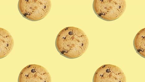 patrón de video de 4k de galletas americanas con pedazos de chocolate disminuyendo sobre un fondo amarillo