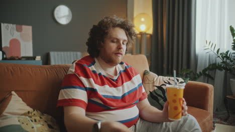 man watching tv and eating snacks