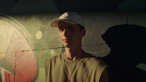 Stylish-man-turning-head-to-camera-in-sunbeams-at-skatepark.-Beautiful-man-face.