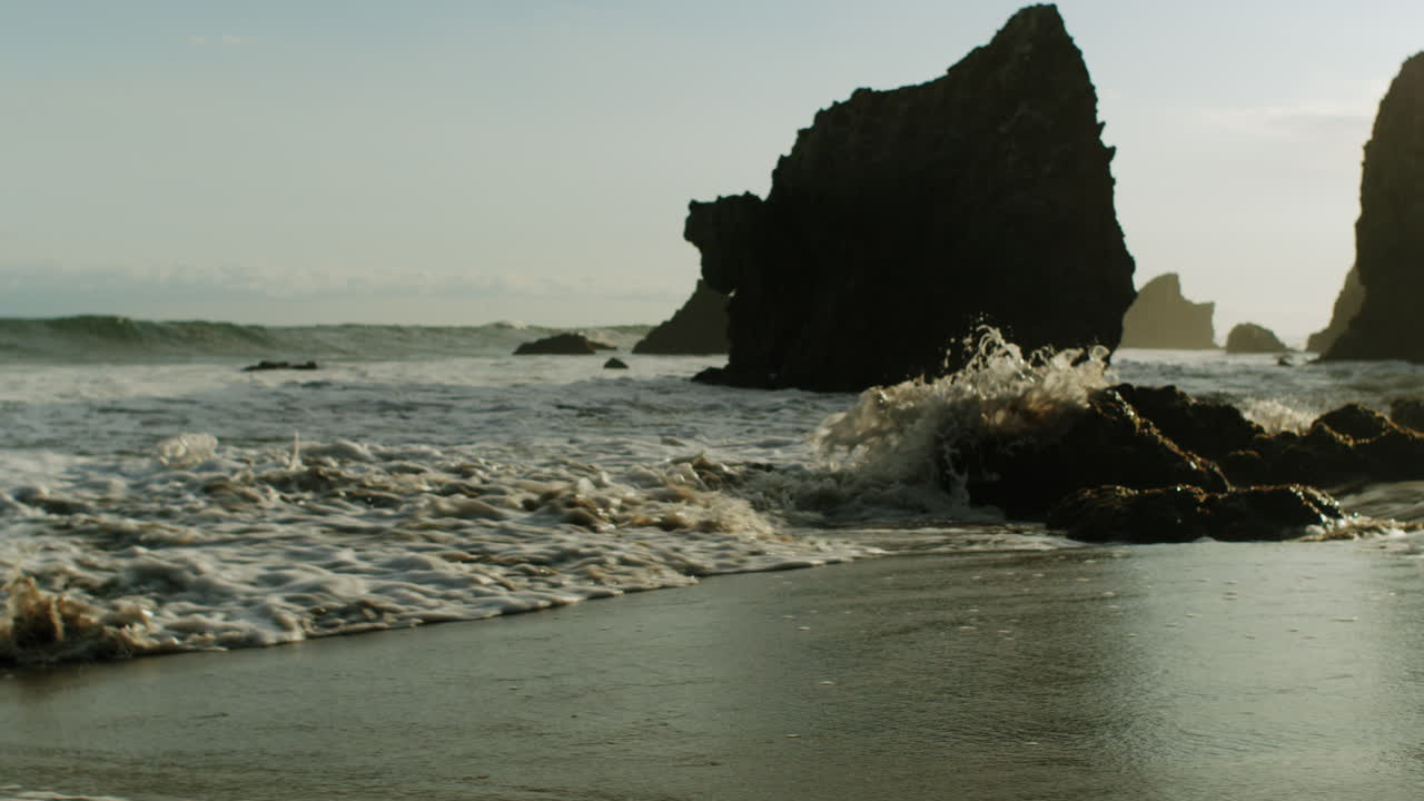 Onde dell'oceano che si infrangono su una spiaggia rocciosa con grandi faraglioni