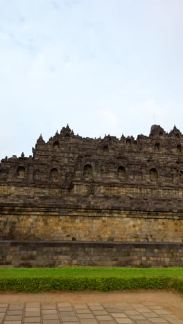 vertical establishing pan of borobudur temple in java, indonesia, intricate historic buddhist carvings in stone