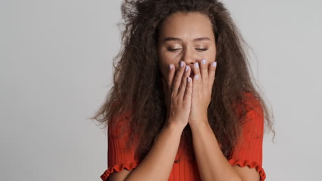 caucasian curly haired woman coughing in front of the camera.