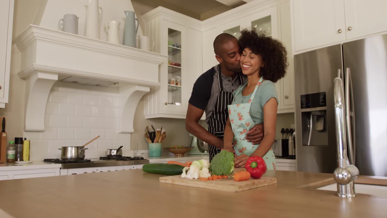 Casal mestiço feliz a cozinhar e a dançar na cozinha deles.