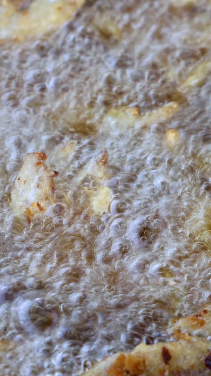 Golden potato fries frying in bubbling oil, extreme close-up, high heat, static camera, daylight