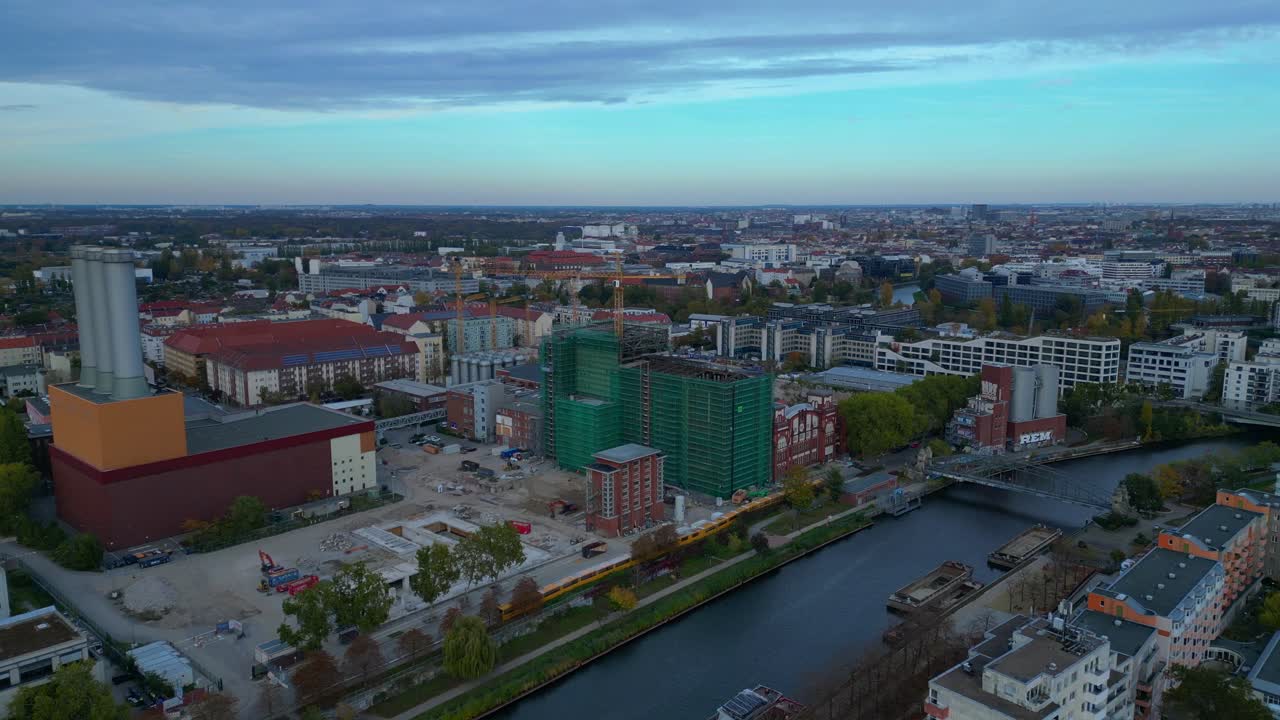 Combined heat and power plant operating in the cityscape by Spree river with new buildings under construction. Nice aerial view flight panorama orbit drone